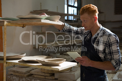 Male potter using digital tablet while working in pottery workshop