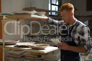 Male potter using digital tablet while working in pottery workshop