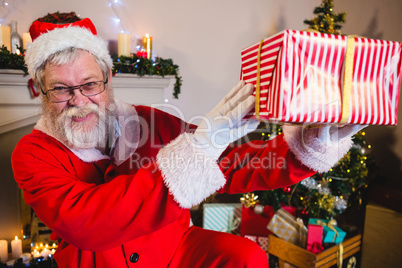 Portrait of santa claus holding a gift box at home