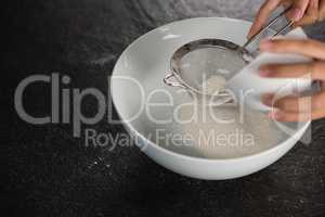 Woman sieving flour into the bowl