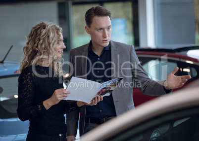 Customer showing brochure to salesman in showroom