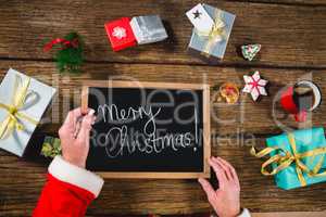 Santa Claus holding a slate with merry christmas text