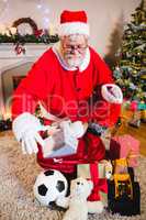 Santa claus placing gift box into gift sack at home