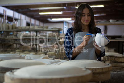 Female potter painting a bowl