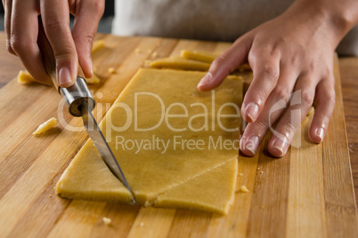 Woman slicing dough on chopping board