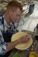 Male potters painting a bowl in pottery workshop