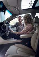 Smiling salesman talking to female customer sitting in car
