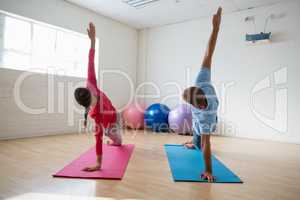 Instructor with student practicing side plank pose in yoga studio