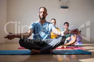 Male instructor with students meditating in club