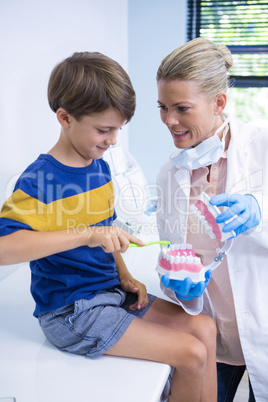 Happy dentist teaching boy brushing teeth