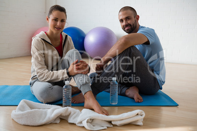 Portrait of student with instructor relaxing in yoga studio