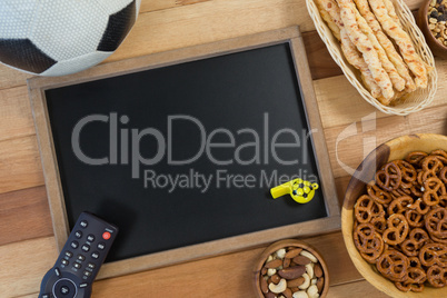 Snacks, football, whistle and slate on wooden table