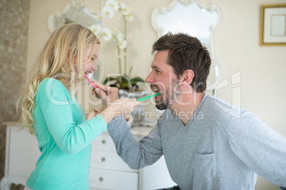 Father and daughter brushing each others teeth