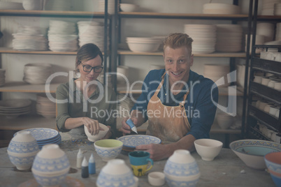 Male and female potter decorating bowl