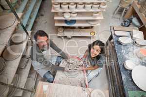 Overhead of male potter assisting female potter