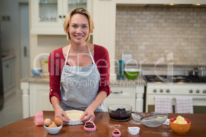 Smiling woman preparing pan cake in kitchen