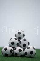 Stack of piled up football soccer balls on artificial grass