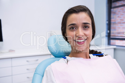 Woman smiling while sitting on chair at dental clinic