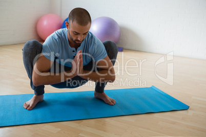 Yoga instructor practicing garland pose in club