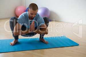 Yoga instructor practicing garland pose in club
