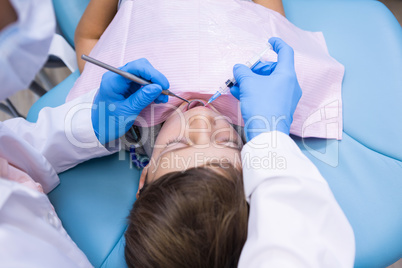 High angle view of dentist holding medical equipment while examining boy