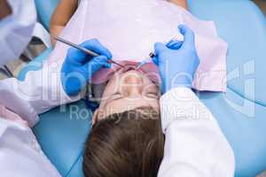 High angle view of dentist holding medical equipment while examining boy