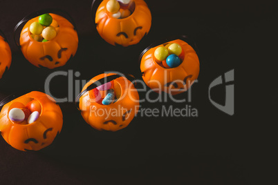 Jack o lantern containers with sweet food over black background