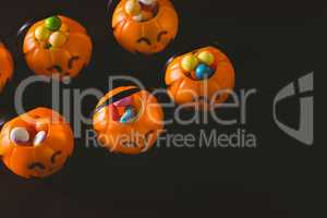 Jack o lantern containers with sweet food over black background
