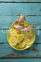Lemon slices and ginger in yellow plate on table