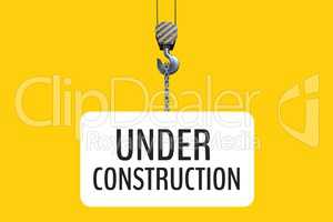 Under construction text hanging of a hook against yellow background