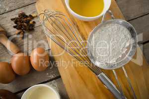 Overhead view of strainer and wire whisk on cutting board