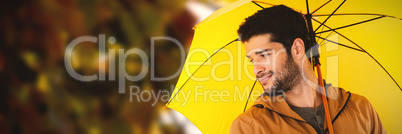 Composite image of smiling man holding yellow umbrella