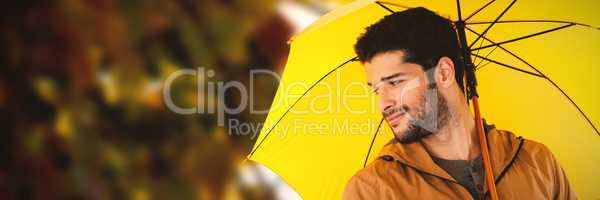 Composite image of smiling man holding yellow umbrella