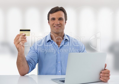 Businessman with laptop at desk with bright background