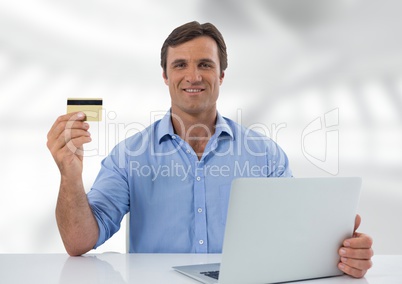 Businessman at desk with laptop with bright background and bank card