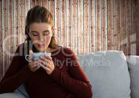 Woman against wood with cup on couch