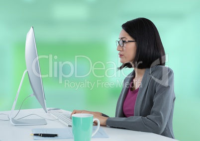 Businesswoman with computer at desk with bright green background