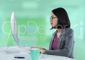 Businesswoman with computer at desk with bright green background