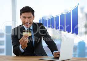 Businessman at desk with laptop and bank card and bar chart incrementing