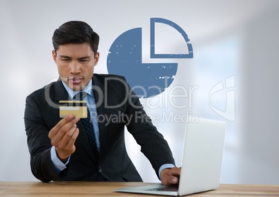 Businessman at desk with laptop and bank card and pie chart