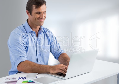 Businessman at desk with laptop with bright background