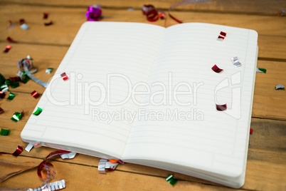 Open note book with confetti on wooden surface