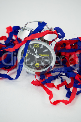 Alarm clock and streamers against white background