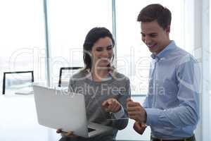 Male executive and female executive working over glass digital tablet