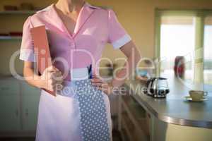 Waitress standing with menu card in restaurant
