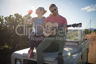 Man playing guitar while woman having a drink