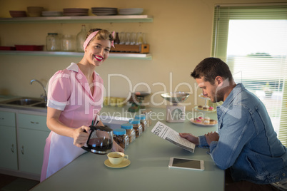 Waitress serving black coffee while man reading newspaper