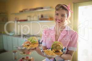 Waitress holding plate of meals in restaurant