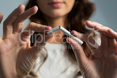 Woman breaking cigarette against white background