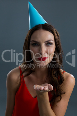 Smiling woman wearing party hat and giving flying kiss